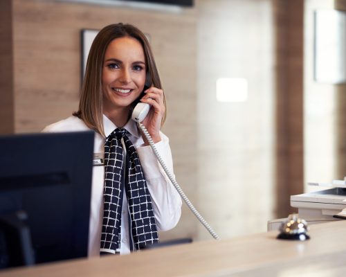 Picture of receptionist answering phone at hotel front desk